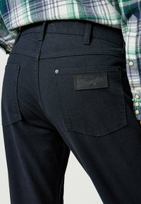 Mörkblå denimjeans med en läderpatch från Wrangler på baksidan, två bakfickor och subtila sömdetaljer.