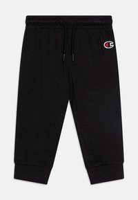 Pantalones de chándal negros hechos de una tela suave, con una cintura elástica y cordón ajustable, y tobillos ajustados. Logotipo bordado en el muslo izquierdo.
