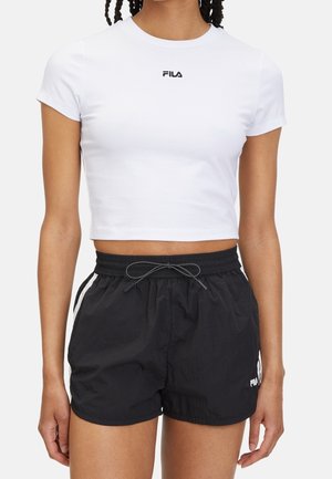 White cropped T-shirt with Fila logo, paired with black lightweight shorts featuring white side accents and elastic waistband with drawstring.