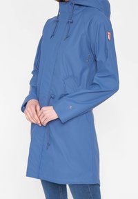 Blauwe waterdichte jas met capuchon, getailleerde taille, voorkruiszakken en een logo-patch. Gladde textuur en een regulier pasvorm ontwerp.