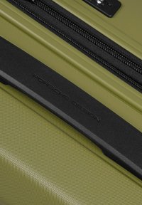 Maleta rígida de color verde oliva con una superficie texturizada, que cuenta con un asa negra grabada con "Porsche Design" y un zipper negro.