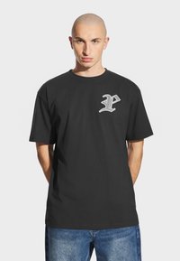 Czarna bawełniana koszulka z krótkim rękawem, z szarym stylizowanym logo "P" na lewej piersi, o luźnym kroju.