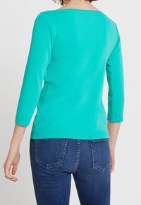 Türkiser Strickpullover mit Dreiviertelärmeln und rundem Halsausschnitt, mit einem gerippten Saum und glatter Textur.