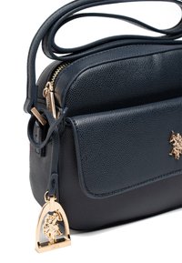 Borsa a mano in pelle blu navy con texture granulosa, hardware dorato, chiusura con zip e un ciondolo metallico con un emblema di un cavallo e cavaliere.