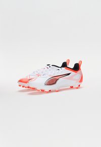 Hvite og oransje fotballsko med et strømlinjeformet design, teksturert overdel, svarte detaljer og markante lisser. Dramatisk grafisk mønster på sidene.