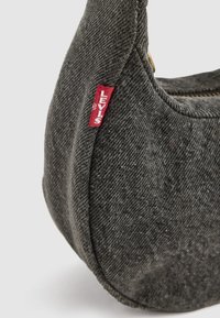 Graue Denim-Handtasche mit geschwungener Form, ausgestattet mit einem sichtbaren roten Levi's-Label; glatte Textur und Reißverschluss-Detail.