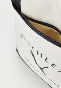 Canvas tas in het wit met marineblauwe accenten. Voorzien van een ritssluiting, binnvoering en een logo-ontwerp met de silhouet van een poema.