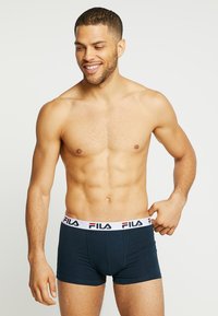 Ciemnogranatowe bokserki z białą elastyczną talią z logo FILA w kolorze czerwonym i czarnym. Gładki materiał, dopasowany krój, długość do połowy uda.