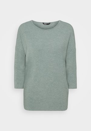 Haut vert clair à manches longues en tissu doux et texturé. Présente un col rond et une coupe ample avec des coutures d'épaule baissées.