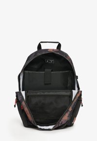Mochila negra con un patrón de camuflaje, cierre con cremallera y un único asa. El interior incluye un bolsillo de malla y compartimentos para organización.