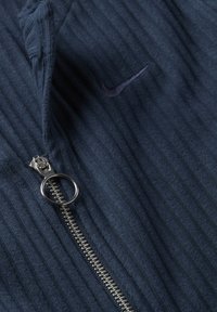 Marineblaue Zip-Up-Jacke mit vertikaler Rippstruktur, silbernem Reißverschluss und gesticktem Logodesign auf der linken Brustseite.