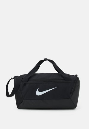 Črn potovalni nahrbtnik z velikim belim logotipom Nike, izdelan iz trpežnega blaga, z dvema ročajema in nastavljivim naramnim trakom.