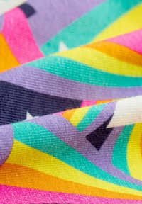 Buntes Gewebe mit einem wellenförmigen Muster in lebhaften Farbtönen von Rosa, Orange, Gelb, Teal und Lila; strukturierte Oberfläche mit leichtem Glanz.