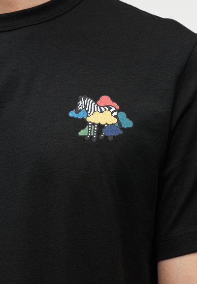 Μαύρο μπλουζάκι με πολύχρωμο γραφικό ενός ζέβρα περιτριγυρισμένου από σύννεφα σε κόκκινο, κίτρινο, μπλε και πράσινο. Κοντά μανίκια, στρογγυλή λαιμόκοψη.