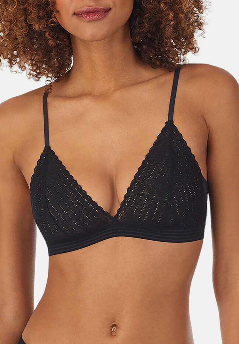 Donna che indossa un reggiseno triangolare in pizzo nero con spalline sottili, mostrata dalla gola fino al girovita su uno sfondo semplice.