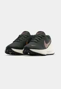 Crne i sive sportske cipele s teksturiranim mrežastim gornjištem, s metalik smeškim Nike znakom, belim srednjim slojem i uzorkovanim potplatom.