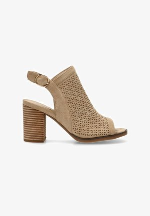 Sandal de tacón abierto en ante beige con patrón floral perforado, correa en el tobillo con herrajes dorados y tacón en bloque apilado.