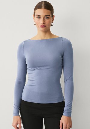 Light blue long-sleeve top with a boat neckline and a fitted design. Made from a smooth, stretch fabric, it features subtle gathers at the sides.