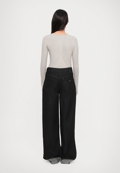 Gray ribbed sweater with long sleeves and a striped pattern on the back, paired with wide-leg black denim jeans. Simple design, no visible logos.
