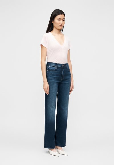 hele roosa lühikeste varrukatega V-kaelusega top tumelainete laiade säärega teksadega. Teksadel on pehme pleek ja ees taskud, mis loob vabaaja ilme.