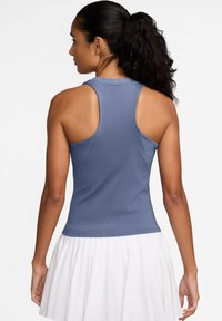 Mouwloze sportieve tanktop in lichtblauw, met een aansluitend design en een gladde textuur. Aangekleed met een open rug en een contrasterende witte rok.
