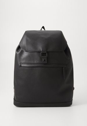 Czarny skórzany plecak z klapką, przednią kieszenią na zamek i górnym uchwytem do noszenia na jednolitym jasnym tle.