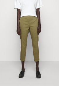 Olijfgroen linnen cropped broeken met een getailleerde pasvorm, voorzien van een gladde textuur en een platte voorkant. Gecombineerd met een wit T-shirt met korte mouwen.