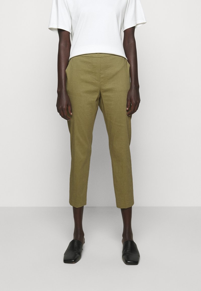 Olijfgroen linnen cropped broeken met een getailleerde pasvorm, voorzien van een gladde textuur en een platte voorkant. Gecombineerd met een wit T-shirt met korte mouwen.