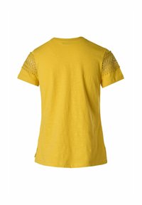 Camisa amarilla de manga corta con detalles de ganchillo en los hombros, escote redondo y aberturas laterales para mayor comodidad.