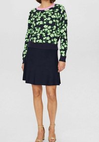 Sweter w kwiatowy wzór w odcieniach zieleni na ciemnogranatowym tle, zestawiony z granatową spódnicą. Jasnoróżowy okrągły dekolt, dopasowany krój, gładka faktura.