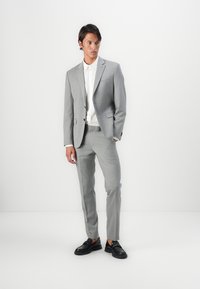 Light gray suit with a textured pattern, paired with a white collared shirt and black shoes, slim-fit tailored design.