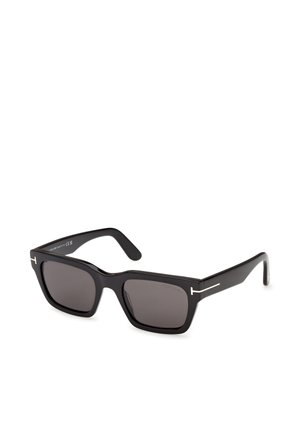 Gafas de sol rectangulares negras con montura gruesa y lentes oscuras, que presentan delgados acentos metálicos plateados con forma de T en las patillas.