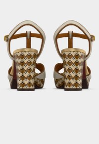 Μπεζ πέδιλα με ψηλό τακούνι και μοτίβο σε ξύλινη βάση, με λουράκι με χρυσές λεπτομέρειες και λείο ταμπά εσωτερικό.