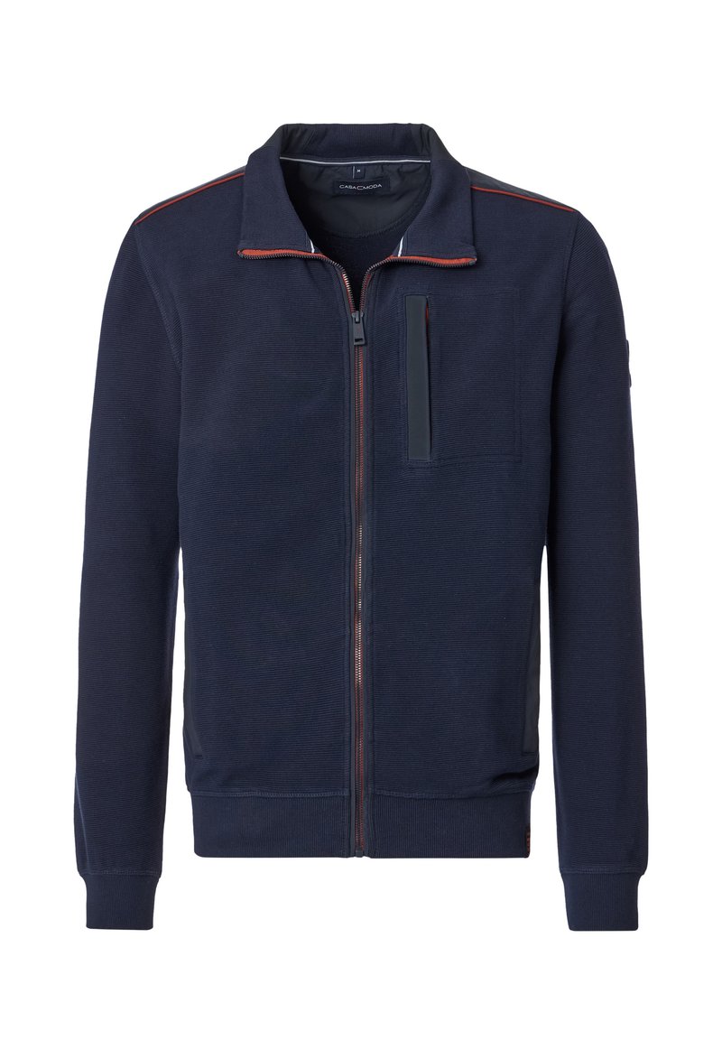 Giacca a zip blu navy realizzata in tessuto testurizzato. Presenta un colletto alto, una tasca sul petto e cuciture rosse a contrasto lungo la cerniera.