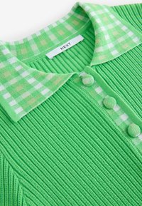 Haut en tricot côtelé vert avec col à carreaux et patte de boutonnage, présentant des boutons recouverts de tissu et une étiquette de marque à l'intérieur de l'encolure.