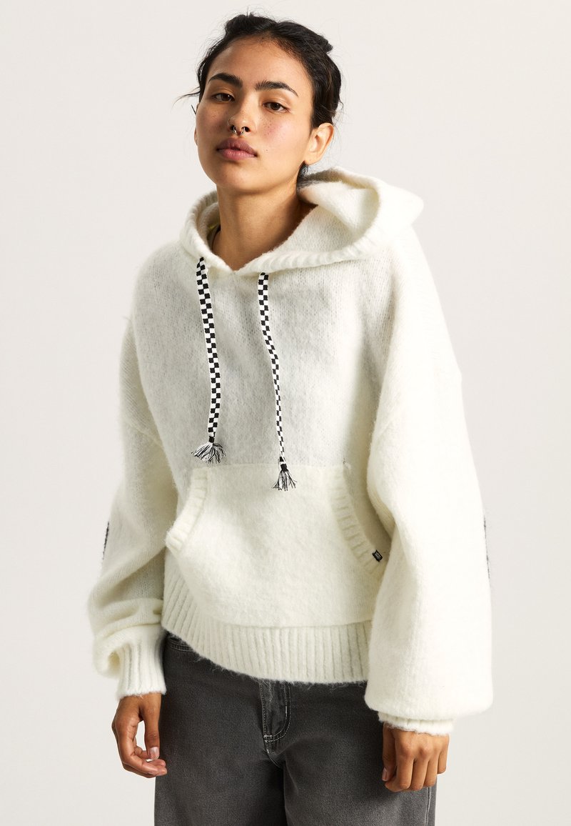 Sweater bianco con cappuccio realizzato in un morbido tessuto testurizzato. Presenta lacci a quadretti neri e una grande tasca frontale con orlo a costine.