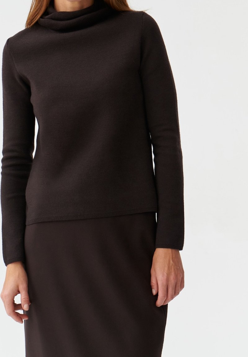 Maglia marrone lavorata a maglia con collo a scialle, maniche lunghe e design aderente, abbinata a una gonna marrone coordinata, tessuto liscio e senza motivi visibili.