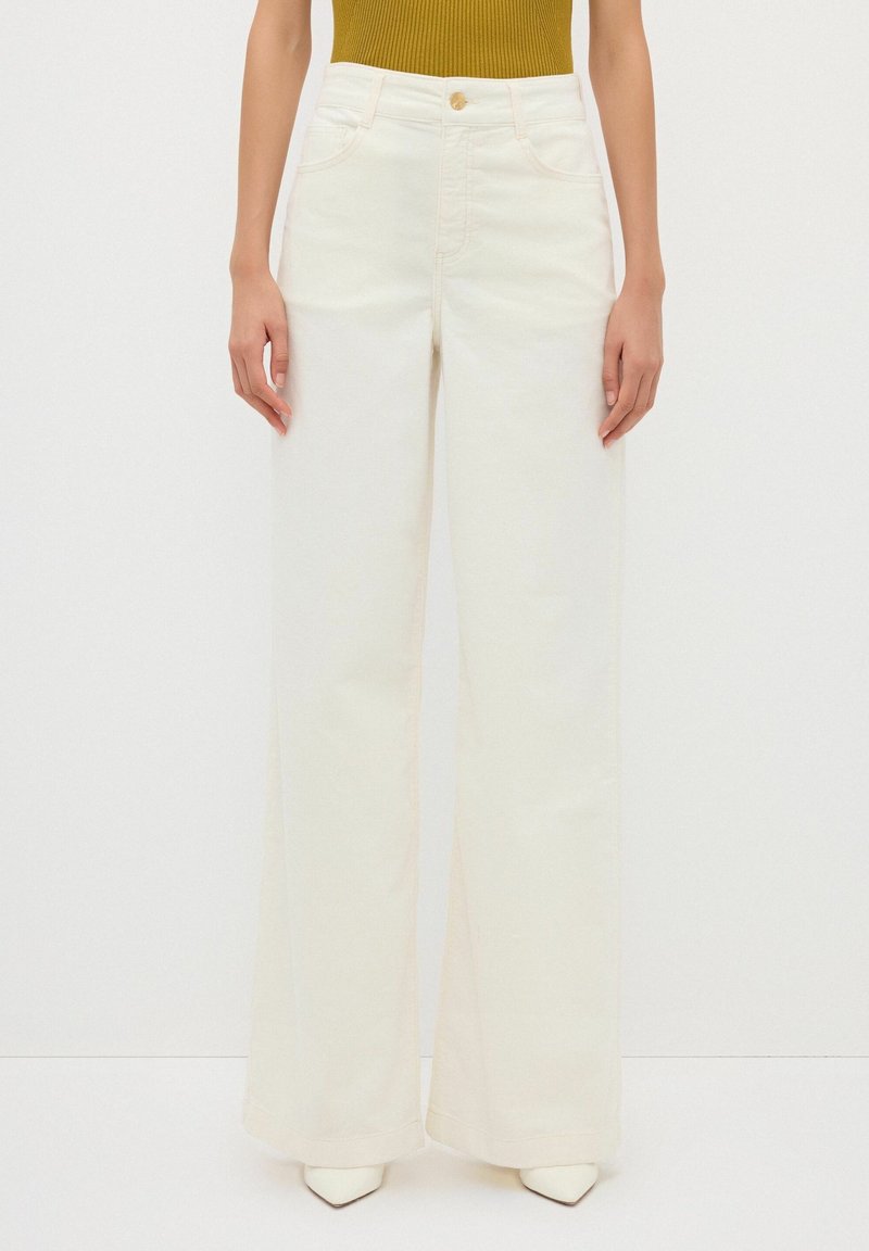 Breda ben, höga byxor i off-white denim, med knappstängning fram, två sidofickor och en mjuk yta.