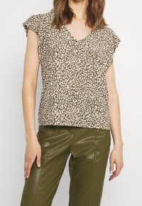Top de estampado de leopardo marrón con mangas cortas tipo volante y escote en V, combinado con pantalones de faux cuero ajustados de tiro alto en color verde oliva.