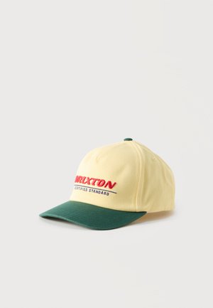 Φωτεινό κίτρινο καπέλο με σκούρο πράσινο γείσο και κουμπί στην κορυφή, με κεντήματα στο μπροστινό πάνελ που γράφουν "BRIXTON CERTIFIED STANDARD" σε κόκκινο και μπλε χρώμα.