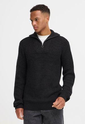 Black knit pullover sweater with a high collar and quarter zip; textured, ribbed material; long sleeves, relaxed fit, and solid design.