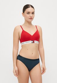 Rode draadloze bralette met verstelbare bandjes, met een logo band. Gecombineerd met marineblauwe hipster slips, beide in een gladde stof.