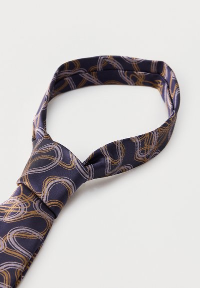 Γραβάτα σε ναυτικό μπλε με αφηρημένα χρυσά και ανοιχτό μοβ κυκλικά μοτίβα γραμμών, χαλαρά δεμένη σε λευκή επιφάνεια.