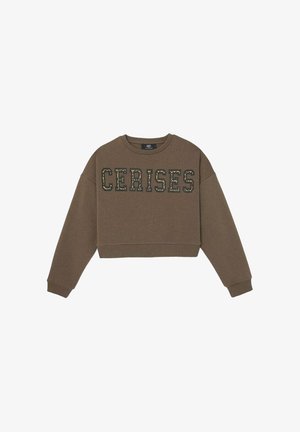 Bruine cropped sweatshirt van zacht materiaal, met de tekst "CERISES" in een camouflestijl patroon op de voorkant. Geribde mouwen en zoom.