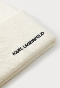 Berretto lavorato a coste bianco con risvolto. "KARL LAGERFELD" è ricamato in nero sul risvolto. Texture morbida, spessore medio.