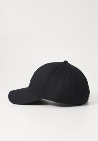 Merikantilainen baseball-lippis, jossa on kaareva lippa, valmistettu teksturoidusta kankaasta, etuosassa ommeltu logopatch ja ilmanvaihtoreiät.