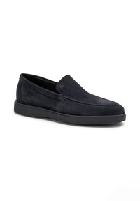 Scarpe slip-on in suede nero con punta arrotondata, cuciture minime e suola in gomma nera spessa. Texture liscia senza hardware visibile.