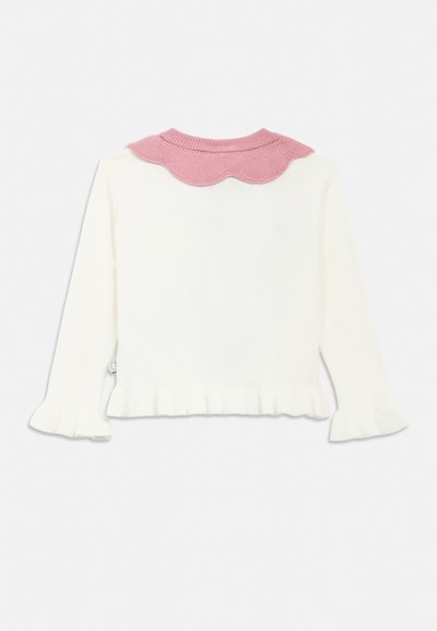 Fehér hosszú ujjú pulóver fodros mandzsettákkal és szegéllyel, rózsaszín hullámos kötött gallérral.