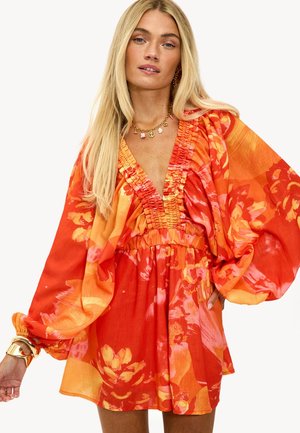 Vestido floral en tonos vibrantes de naranja y rosa, con escote en V, pecho recogido y mangas amplias. Hecho de tejido ligero.