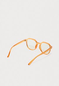 Rame de ochelari rectangulare translucide, de culoare portocalie, cu lentile clare, plasate pe o suprafață gri deschis.